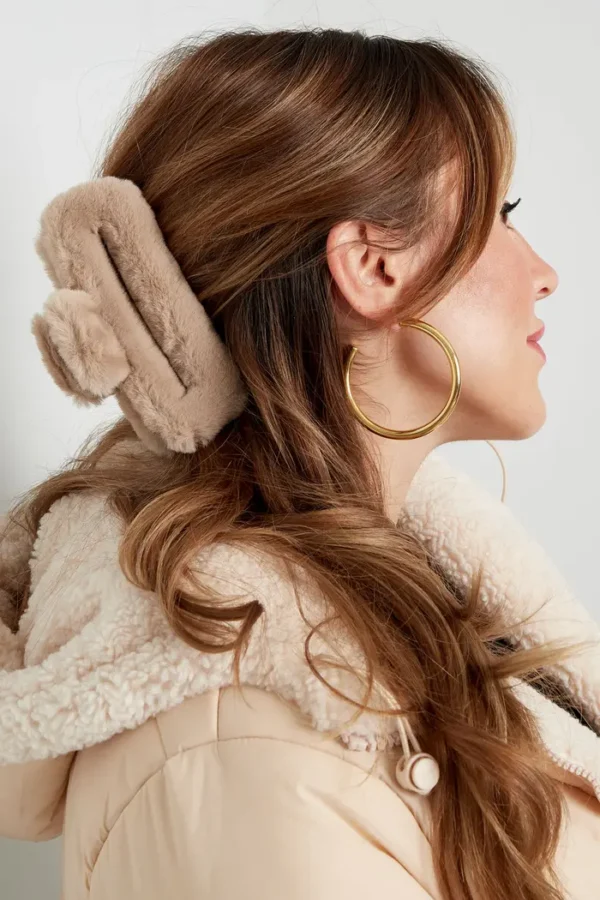 Vrouw met oorwarmers en gouden oorbellen.