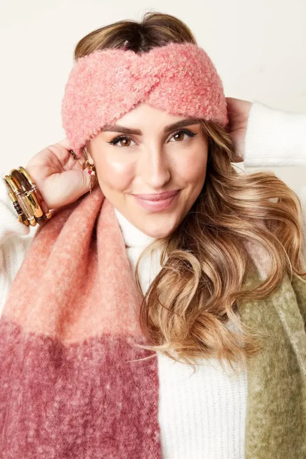 Vrouw met roze haarband en kleurrijke sjaal glimlacht.
