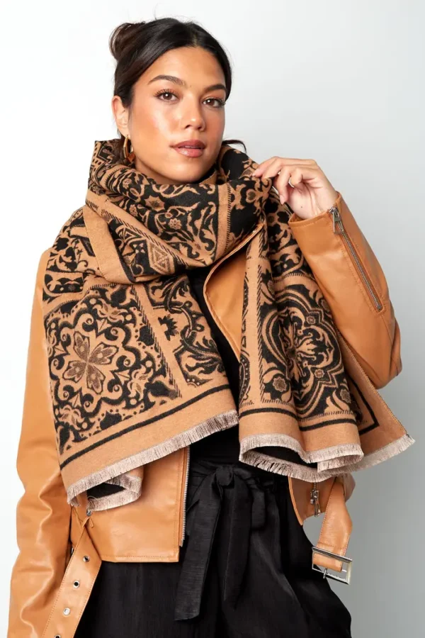 Vrouw toont bruine sjaal met patroon.