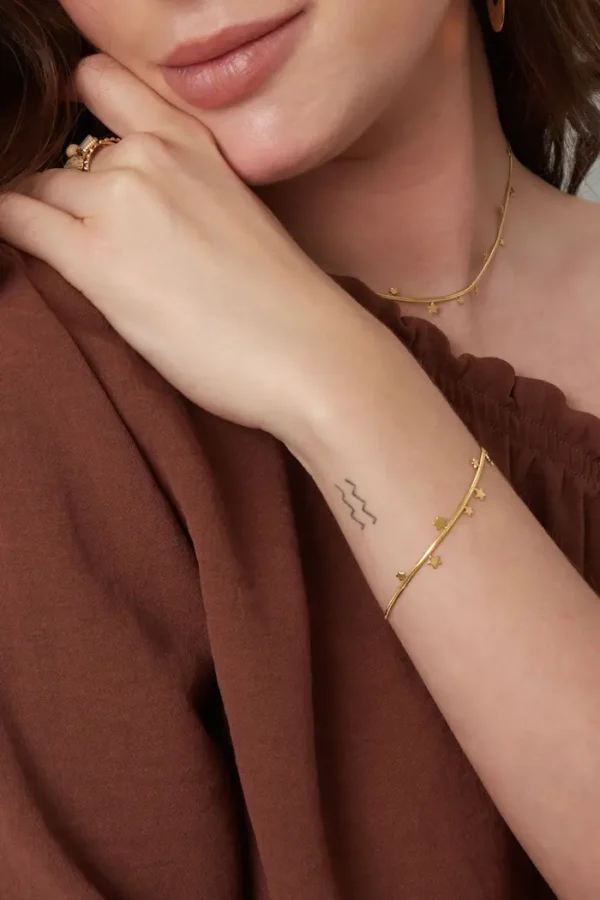 Vrouw toont sieraden: halsketting en armband.