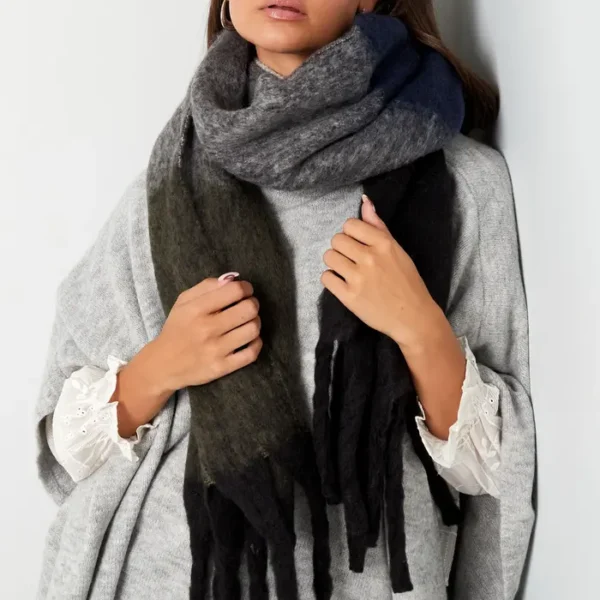 Vrouw met grijze wollen sjaal en lichte trui.