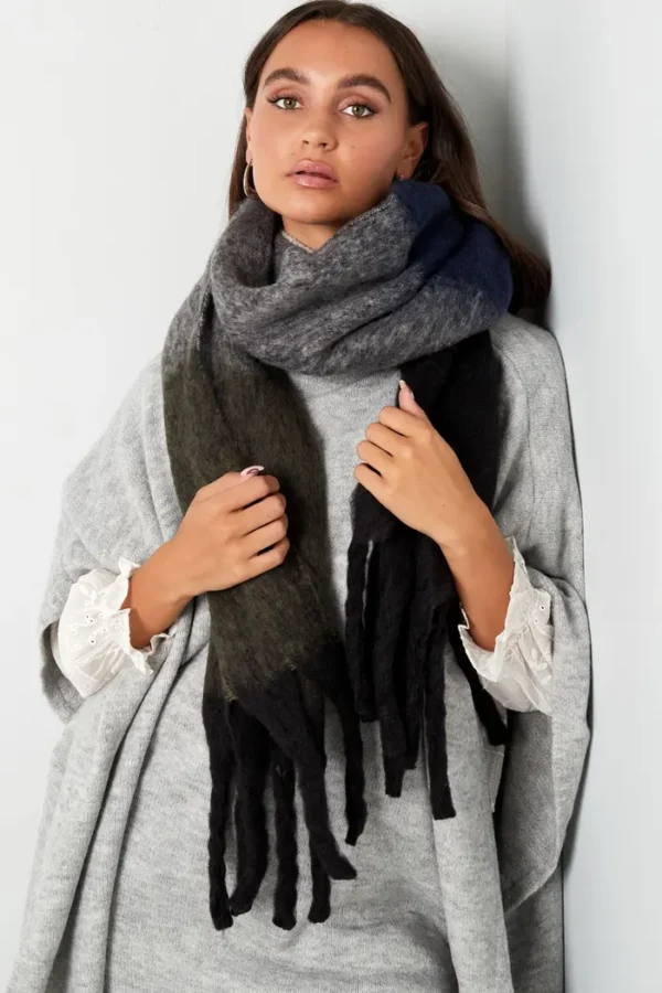 Vrouw met grijze wollen sjaal en lichte trui.