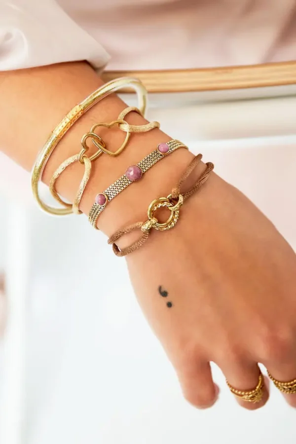 Armbanden in goudtinten om een vrouwelijke pols.